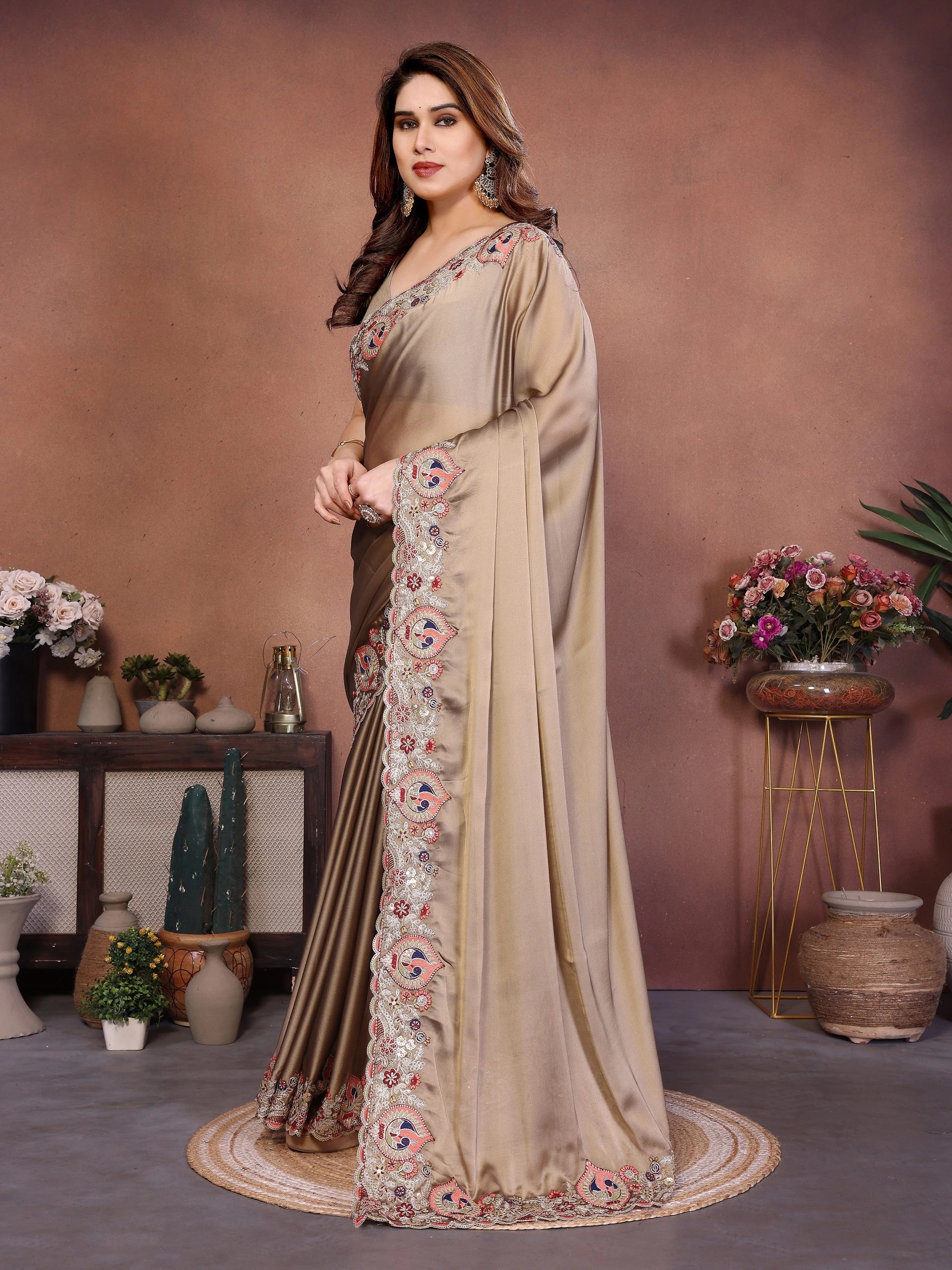 Woman wearing a beige saree with floral patterns in a decorated room.